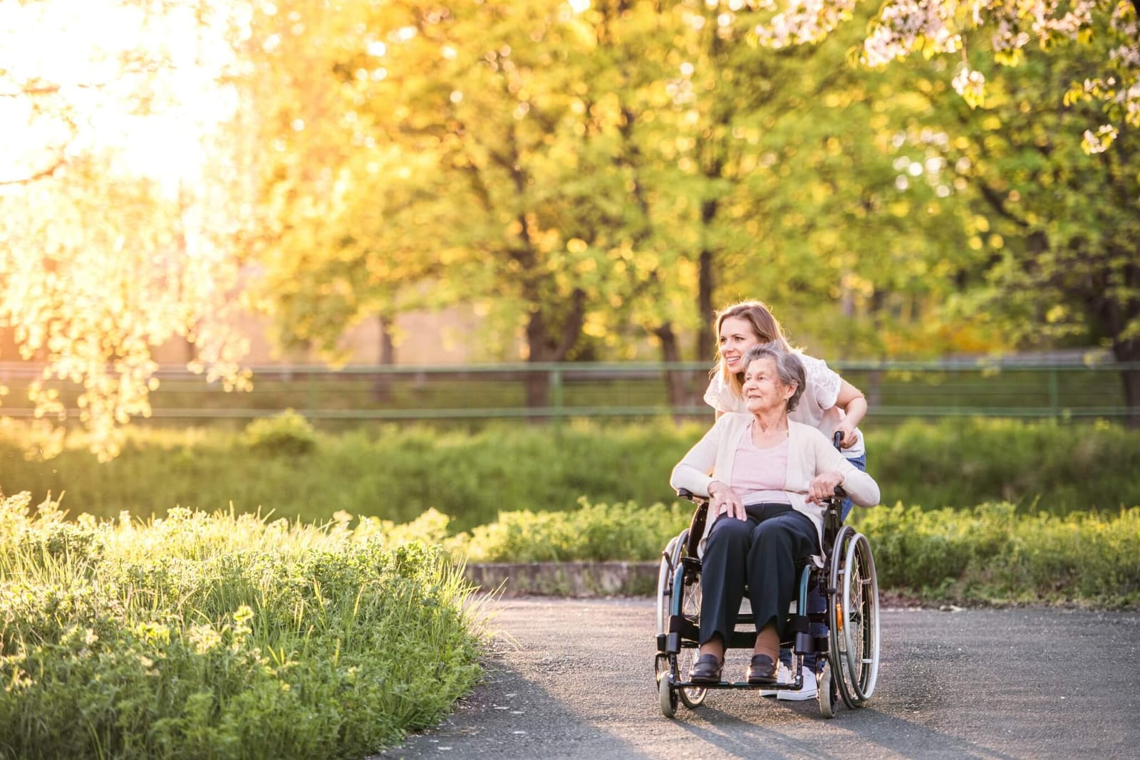 woman with dementia being pushed in a wheelchair through an outdoor setting