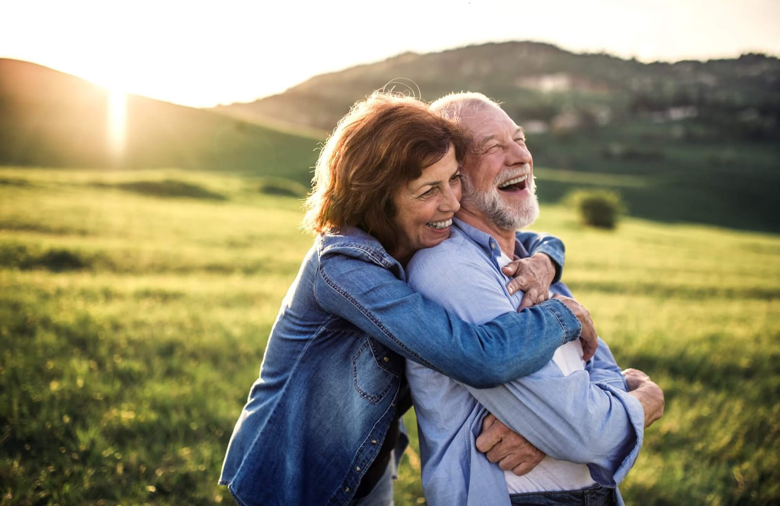 woman hugging a man with dementia while we smiles off into the distance