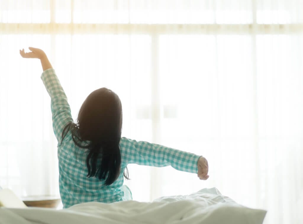 back of dark-haired child waking up stretching after sleep - creating a back-to-school routine