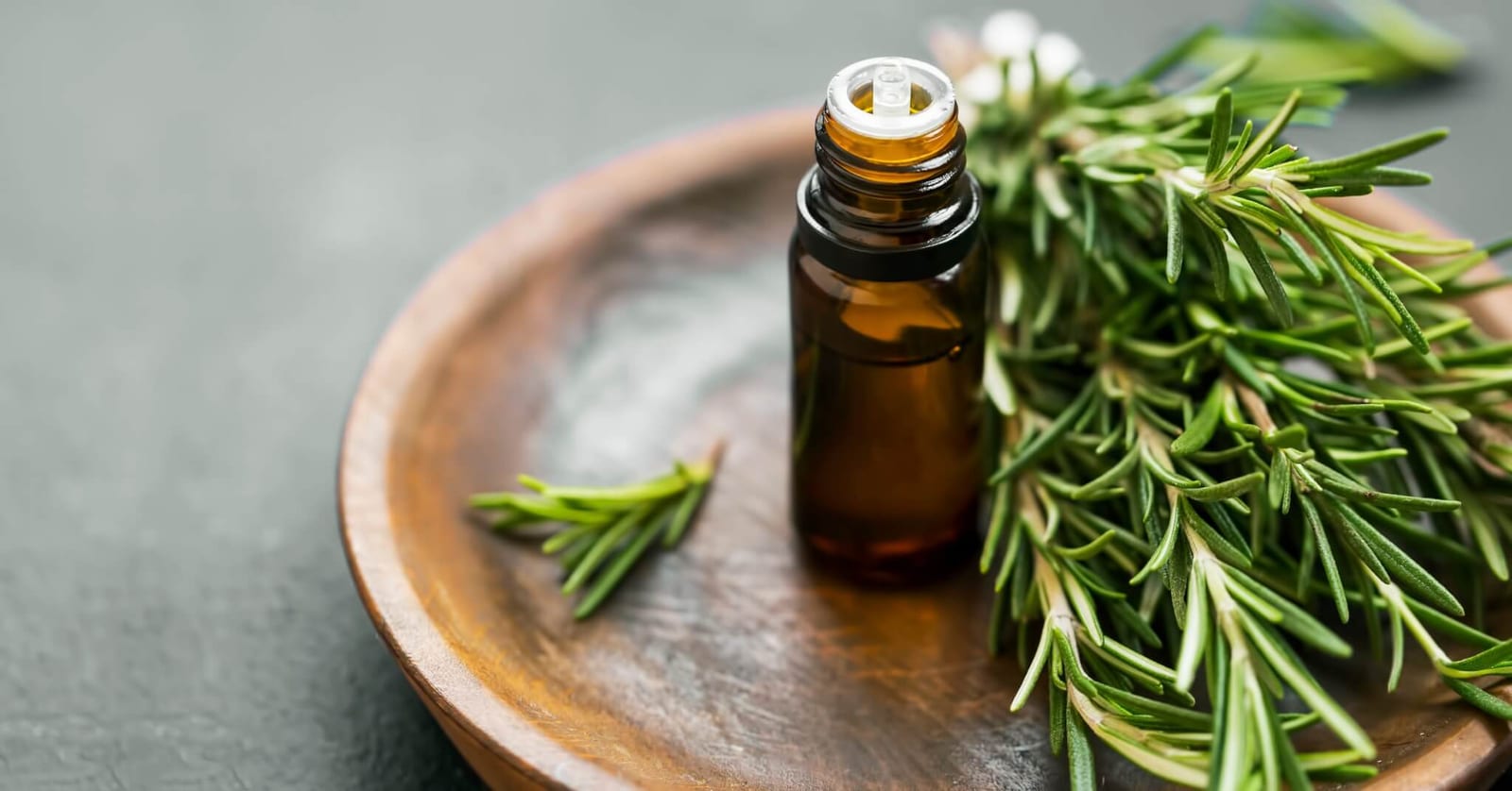 dropper bottle sitting next to a bunch of rosemary sprigs