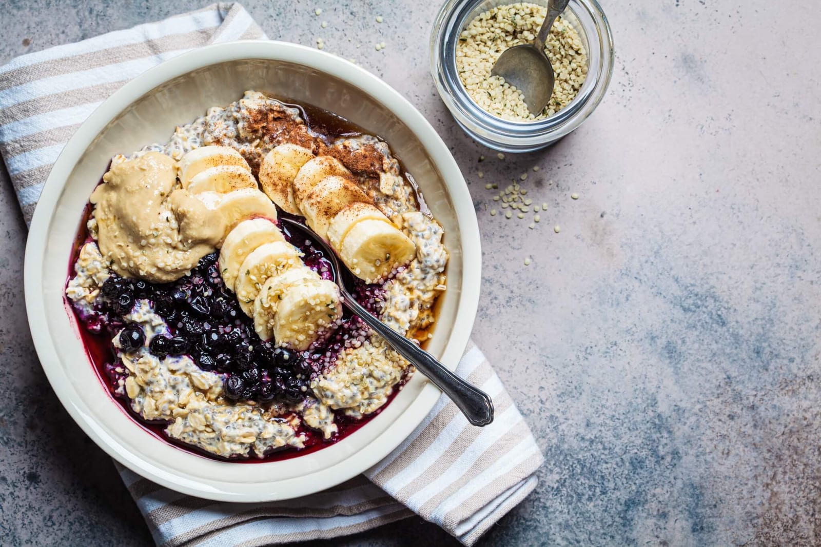 high fiber overnight oats bowl with foods including banana, blueberry, and peanut butter as part of a colon health diet