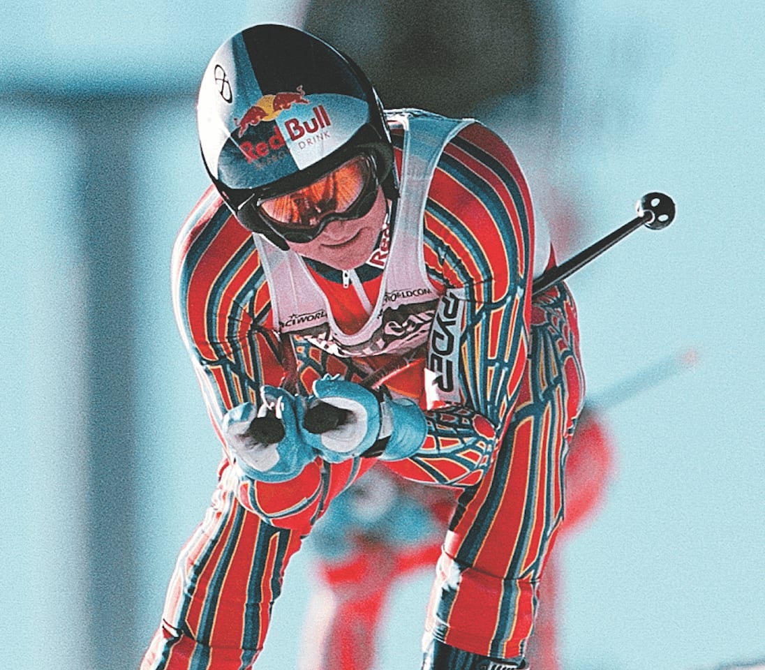 man skiing in a striped ski suit and a Red Bull helmet