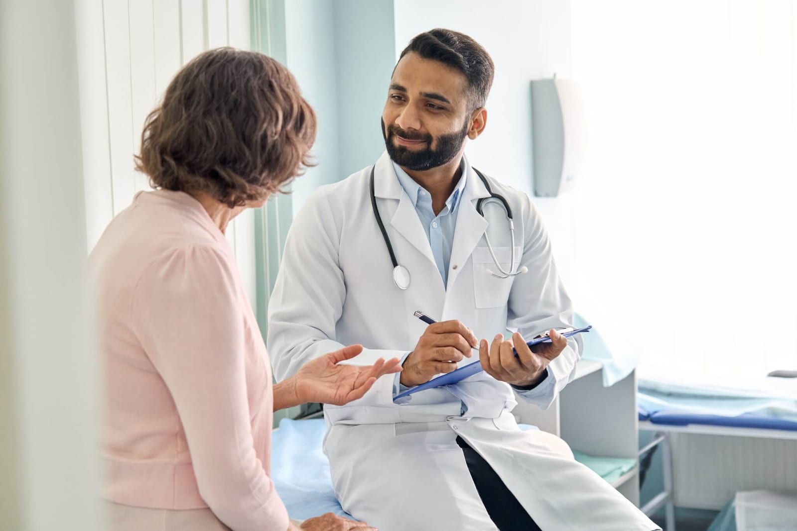 doctor in a white coat discussing the new CRC colorectal cancer screening guidelines and testing recommendations with his female patient