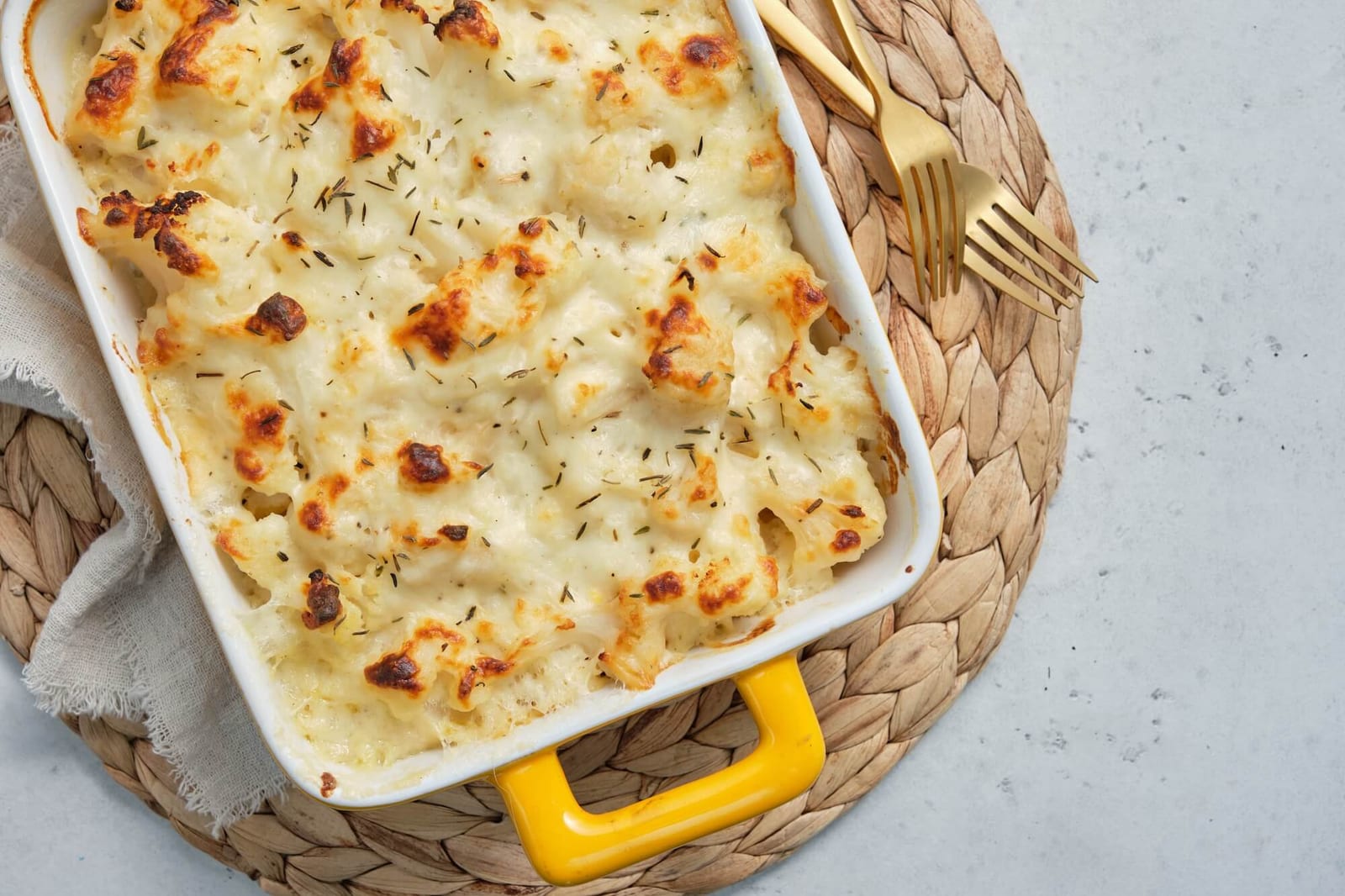 A casserole dish filled with macaroni and cheese with cauliflower, topped with melted cheese and breadcrumbs, ready to be baked to golden perfection.dinner ideas picky eater