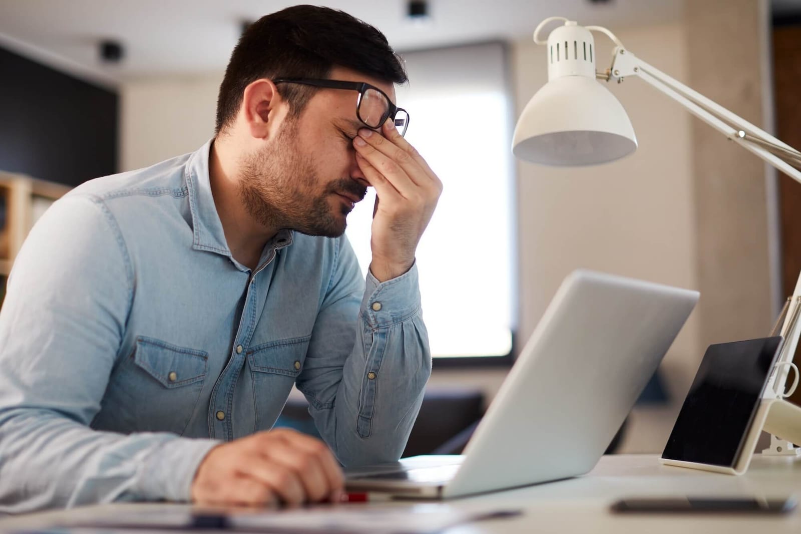 Young man has a headache at work while working on a laptop
