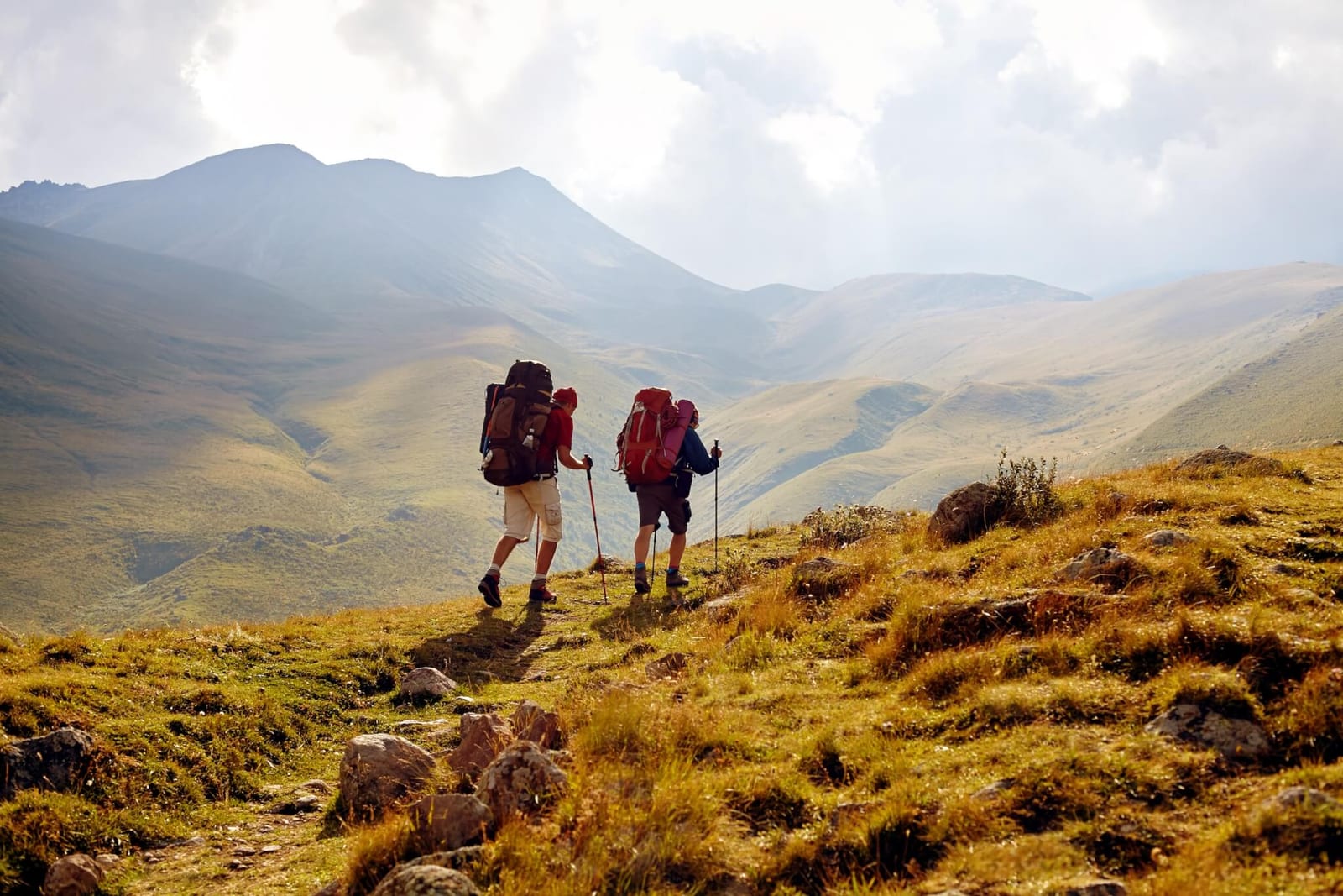 two backpackers using trekking poles on their long hike to reduce the amount of weight on their feet to help avoid getting blisters on the trail