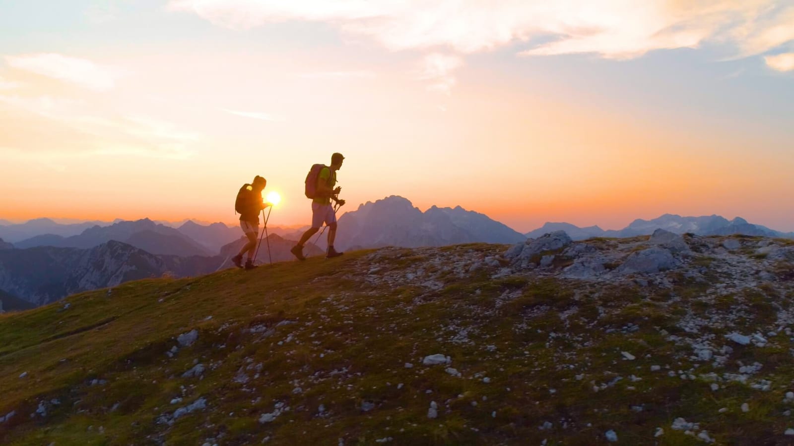 duo hiking up a mountain ridge during golden hour