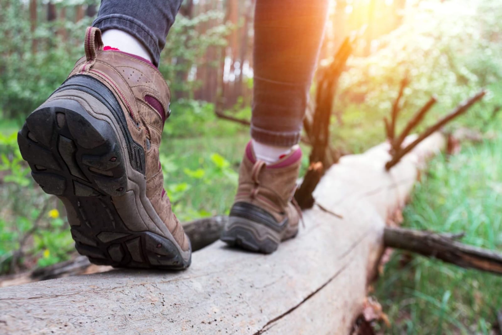 close up image of feet in hiking boots walking on a log