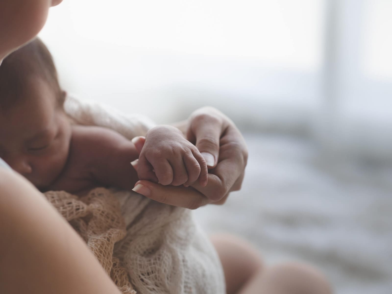 Close up Mother holding hands Asian female newborn baby and sunlight in the morning. Cute little girl three weeks old. Health, care, love, relationship concept.