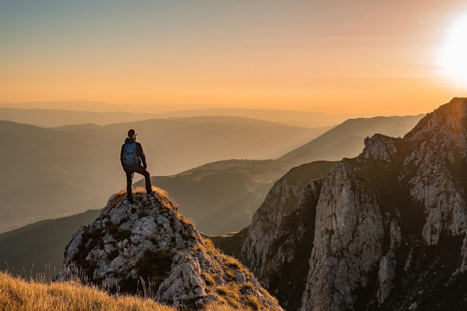 man standing on the top of a mountain at sunset