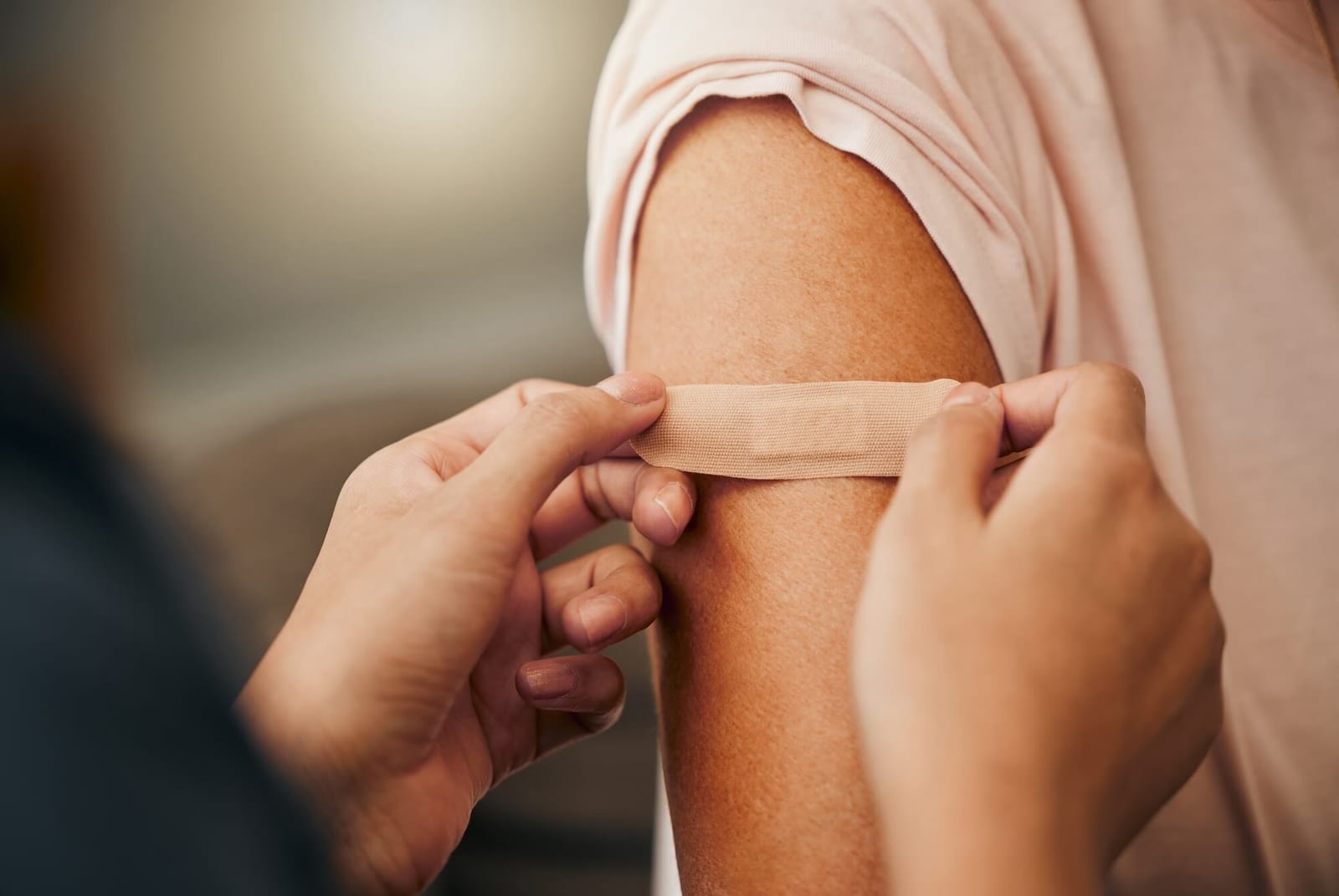 Covid, vaccine and plaster with a doctor and patient consulting in an appointment or checkup at home. Nurse, healthcare and trust with a health professional using a bandaid on an arm after medication.